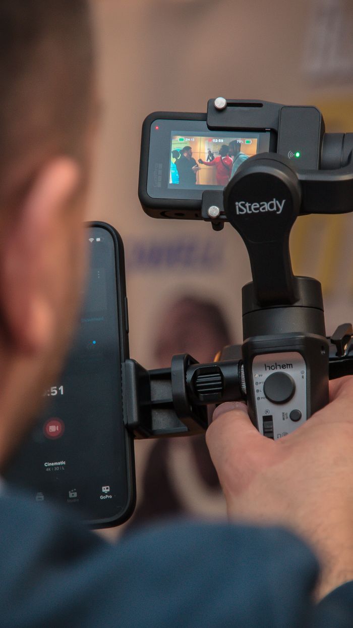 home-services-01 Un homme utilise un stabilisateur pour smartphone afin de filmer, garantissant des images fluides grâce à une technologie moderne.